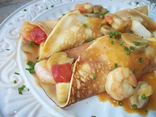 seafood crepes with shrimp, fish and scallops in a tomato-saffron sauce